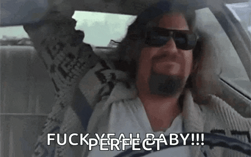 a man with a beard is sitting in a car with his arms in the air and says `` fuck yeah baby '' .
