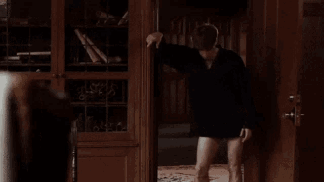 a man without a shirt is standing in a doorway and says hmm , a mystery !