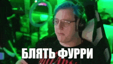 a man with blue hair and glasses is sitting in a chair in front of a green screen .