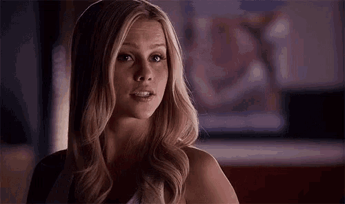 a woman with long blonde hair is looking at the camera .