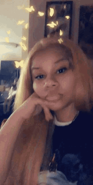 a woman with long blonde hair is making a funny face with her hand on her face .