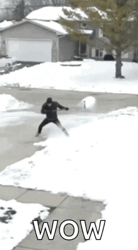 a man is standing in the snow holding a snowball and the word wow is on the sidewalk