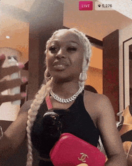 a woman is holding a red chanel purse in front of a live button