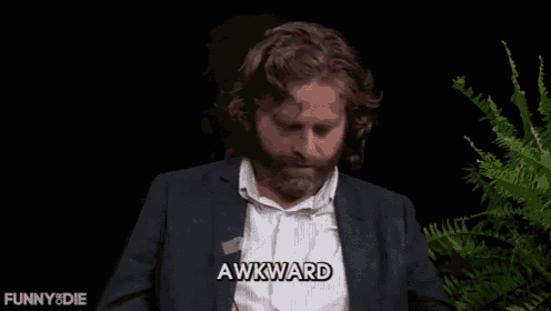 a man in a suit says awkward in front of a fern