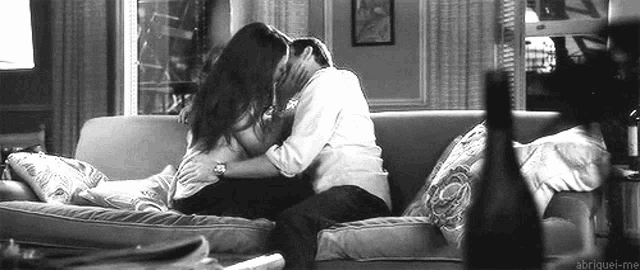 a couple is kissing on a couch in a living room .