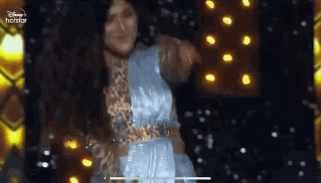 a woman is dancing on a stage with lights in the background .