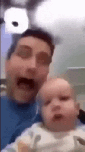 a man is holding a baby in his arms while making a funny face .