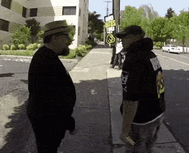 two men are standing on a sidewalk in front of a sign that says ' lives matter '