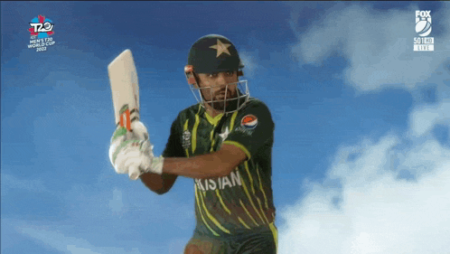 a man in a green pakistan jersey is holding a bat in front of a blue sky