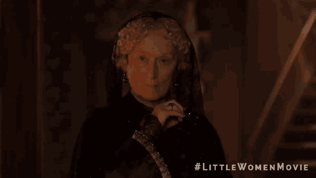 a woman in a black dress with #littlewomenmovie on the bottom right
