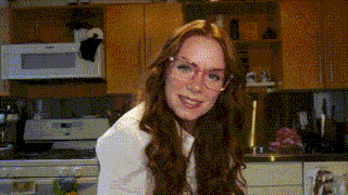 a woman wearing glasses is sitting in a kitchen