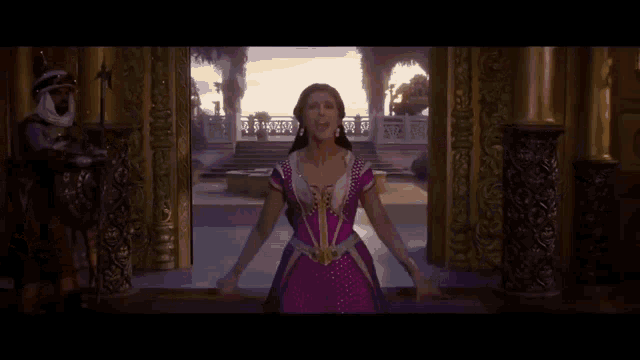 a woman in a pink dress is standing in front of a window in a room .
