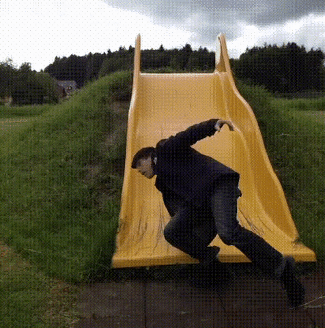 a man is sliding down a yellow slide