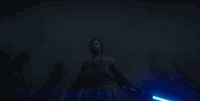 a man is holding a light saber in the dark