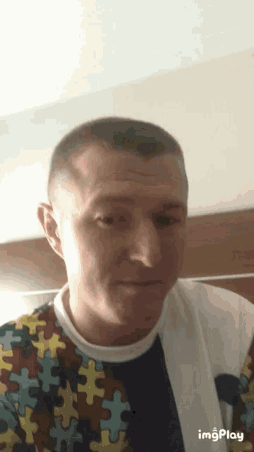 a man is wearing a shirt with puzzle pieces on it and the word imgplay is below him