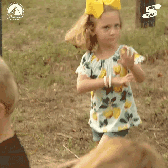 a little girl with a yellow bow on her head is wearing a shirt that has lemons on it