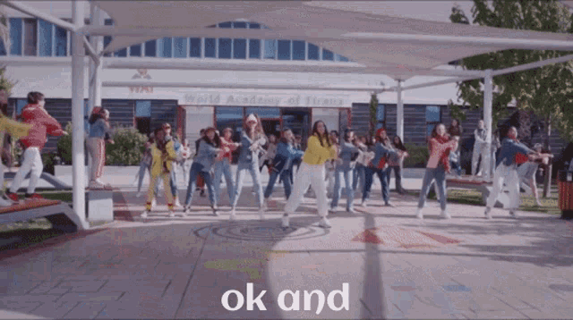 a group of young girls are dancing in front of a building that says world academy of tirana