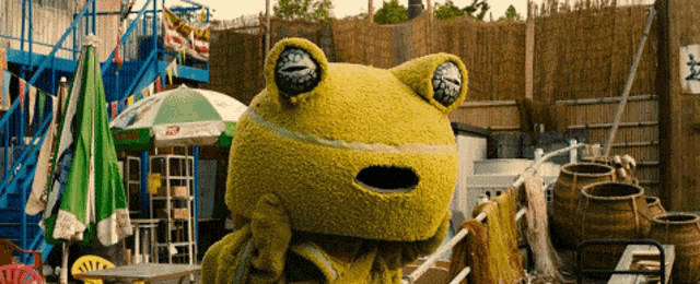 a frog mascot is standing in front of an umbrella that says ' ice cream ' on it