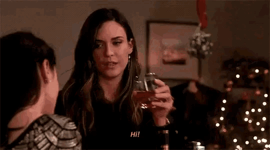 a group of women are sitting at a table drinking wine and talking .