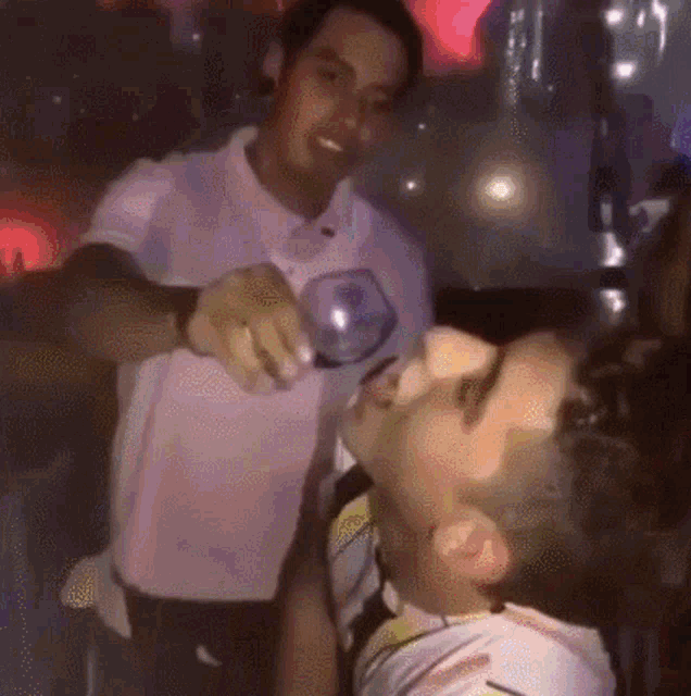a man is pouring a glass of wine into another man 's face