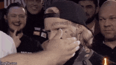 a man with a tattoo on his forehead is being touched by a group of people .