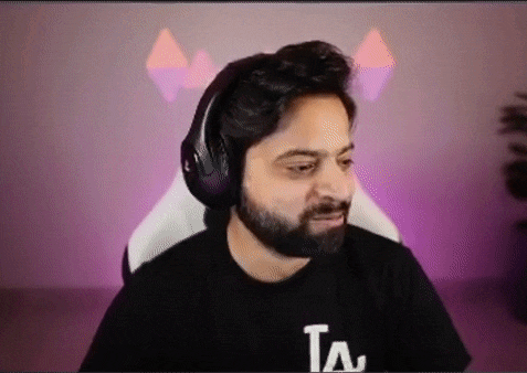 a man with a beard is wearing headphones and a la shirt .