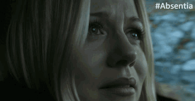 a close up of a woman 's face with #absentia written below it
