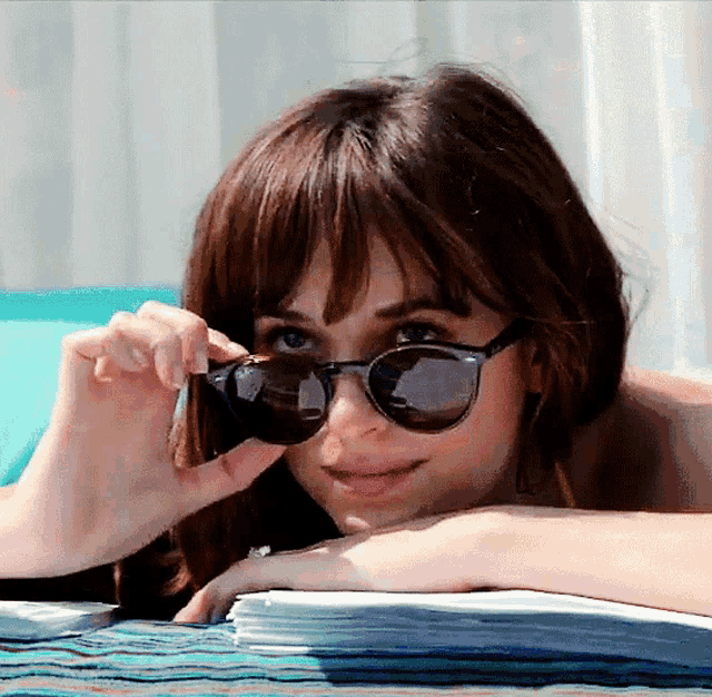 a woman wearing sunglasses is laying on a blue blanket