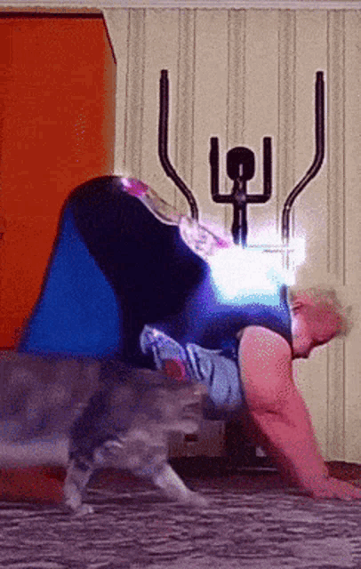 a person is doing push ups with a cat behind them