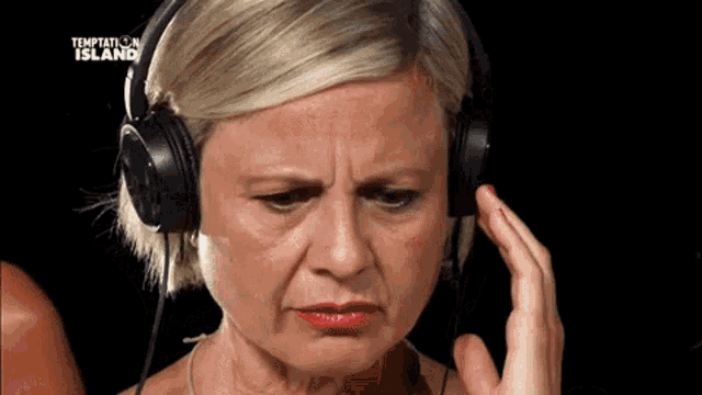 a woman wearing headphones with temptation island written on the screen behind her