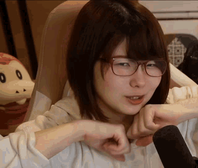a woman wearing glasses is sitting in front of a microphone and making a face .