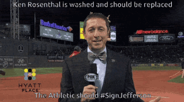 a man in a suit and bow tie holds a microphone in front of a fox advertisement