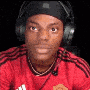 a man wearing headphones and a red shirt is looking at the camera