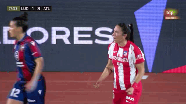 a woman in a red and white striped shirt with the number 12 on her shorts
