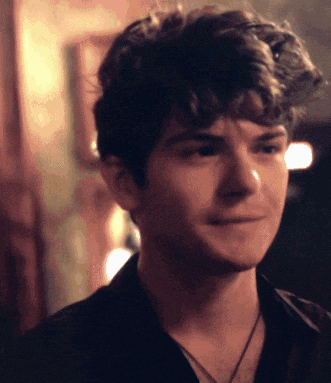 a young man with curly hair is wearing a black shirt