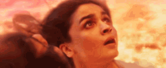 a close up of a woman 's face with a fire background .