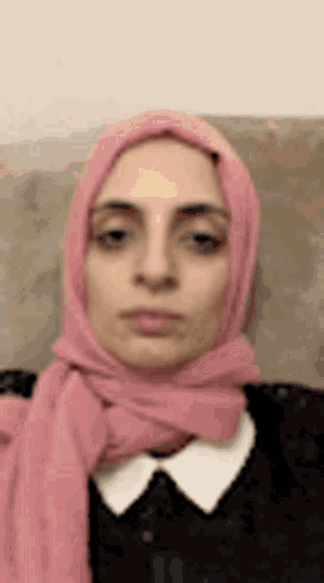 a woman wearing a pink scarf is sitting on a couch .