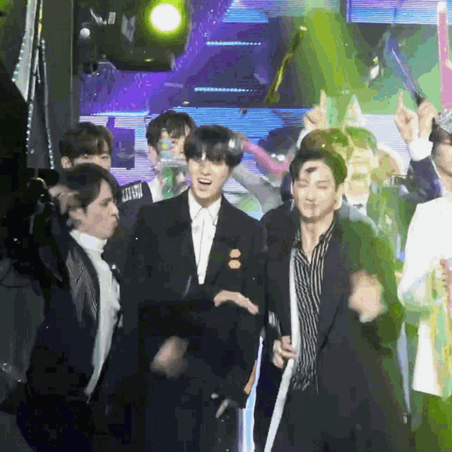a group of young men are dancing in front of a green light