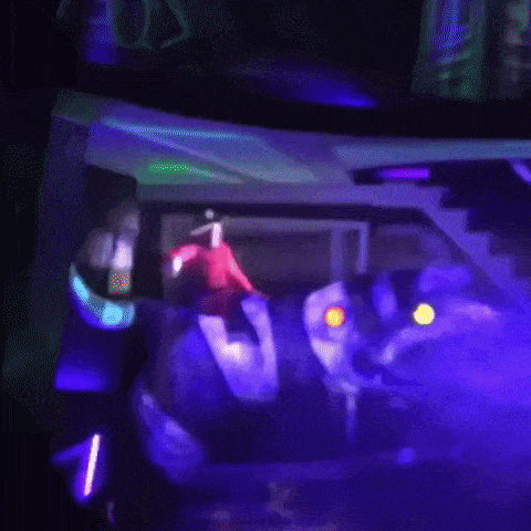 a man in a red jacket is standing in front of a car in a dark room with purple lights .