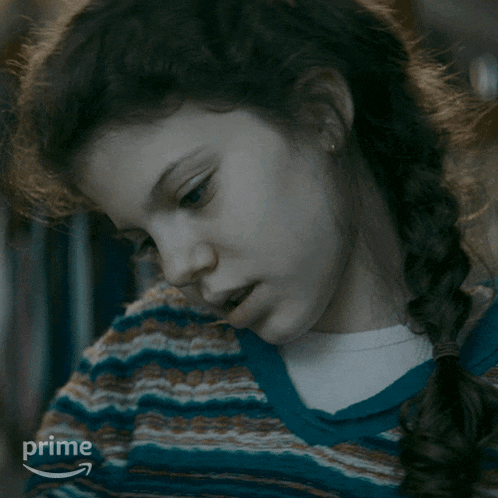 a girl with a braided ponytail looks at the camera with an amazon prime logo in the background