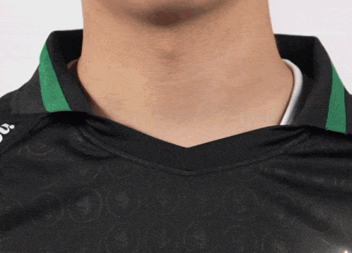 a man wearing a black shirt with a green collar has a white shirt underneath