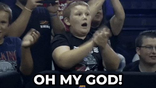 a young boy is clapping his hands in the air while sitting in a stadium .