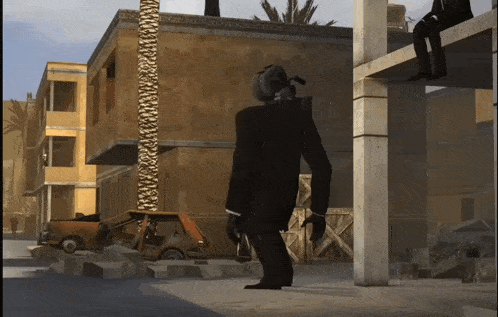 a man in a suit stands in front of a building with a car in the background