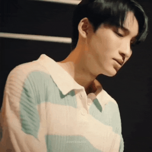 a close up of a young man wearing a striped shirt and looking down .