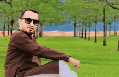 a man wearing sunglasses is sitting in a park