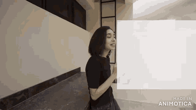 a woman in a black shirt is standing in a room with a white board .