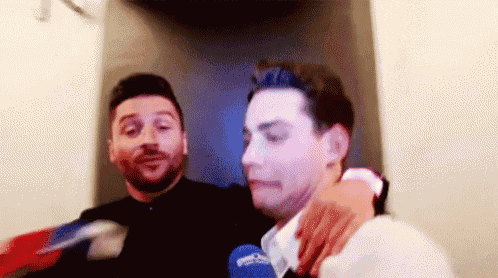 two men are standing next to each other in a room .