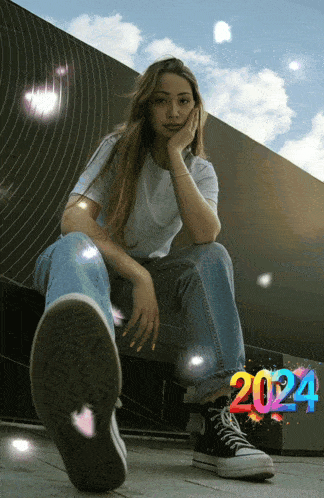 a woman sitting in front of a wall with the number 2024 behind her