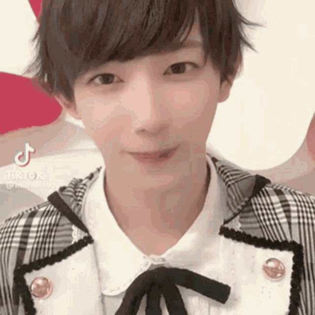 a young man with short hair is wearing a plaid jacket and a white shirt with a bow .
