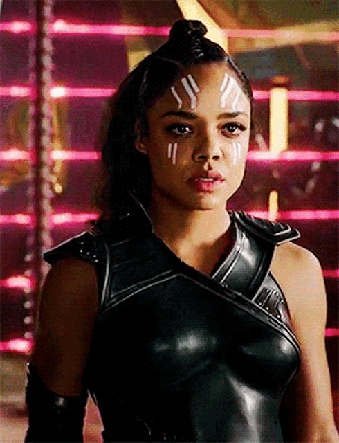 a woman in a black leather outfit with white paint on her face .